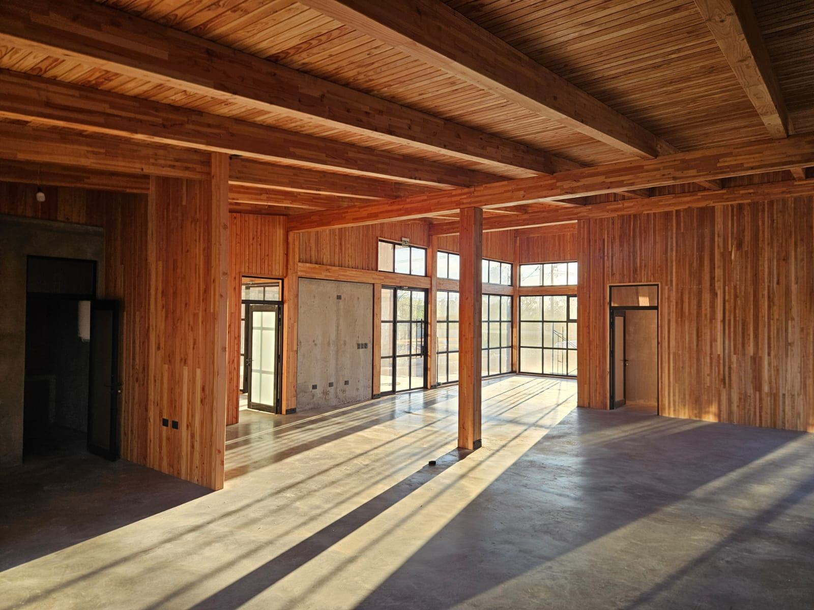 Interior de Nexo Parque: vigas de madera laminada, ventanales y piso de hormigón pulido